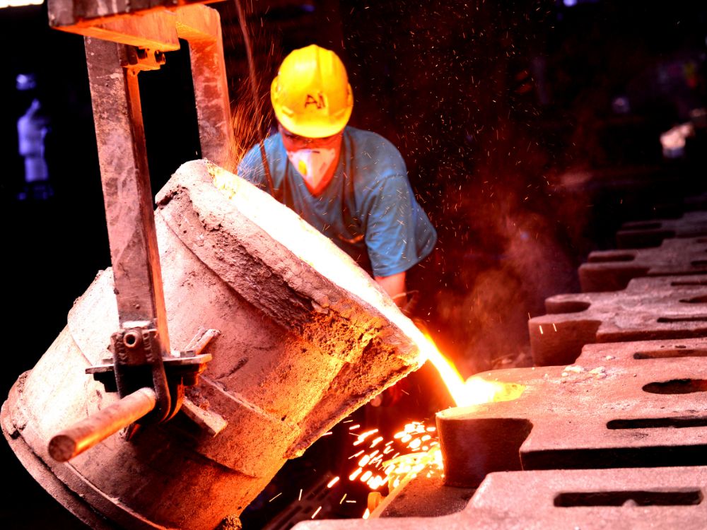 Processo de vazamento de metal líquido em molde industrial, representando a fabricação e explicação técnica sobre O que é ferro nodular.