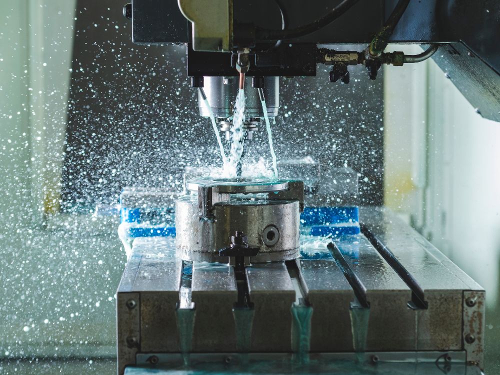 Máquina CNC realizando corte com fluido refrigerante demonstrando o que é usinagem industrial.