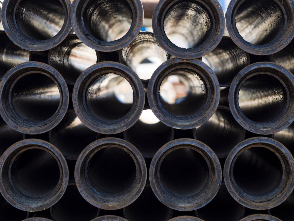 Tipos de ferro em tubos metálicos industriais alinhados, mostrando aplicação em sistemas de condução e estruturas metálicas.