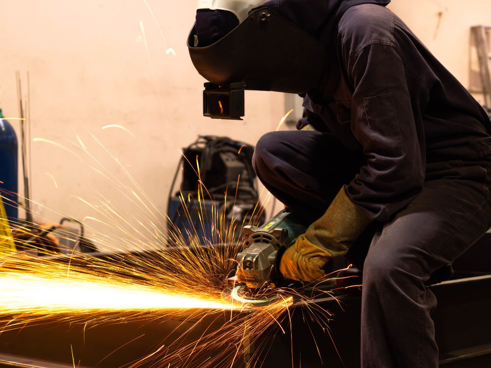 Operador utilizando esmerilhadeira em acabamento industrial, atividade comum em reparos onde tem como soldar ferro fundido com precisão e durabilidade.